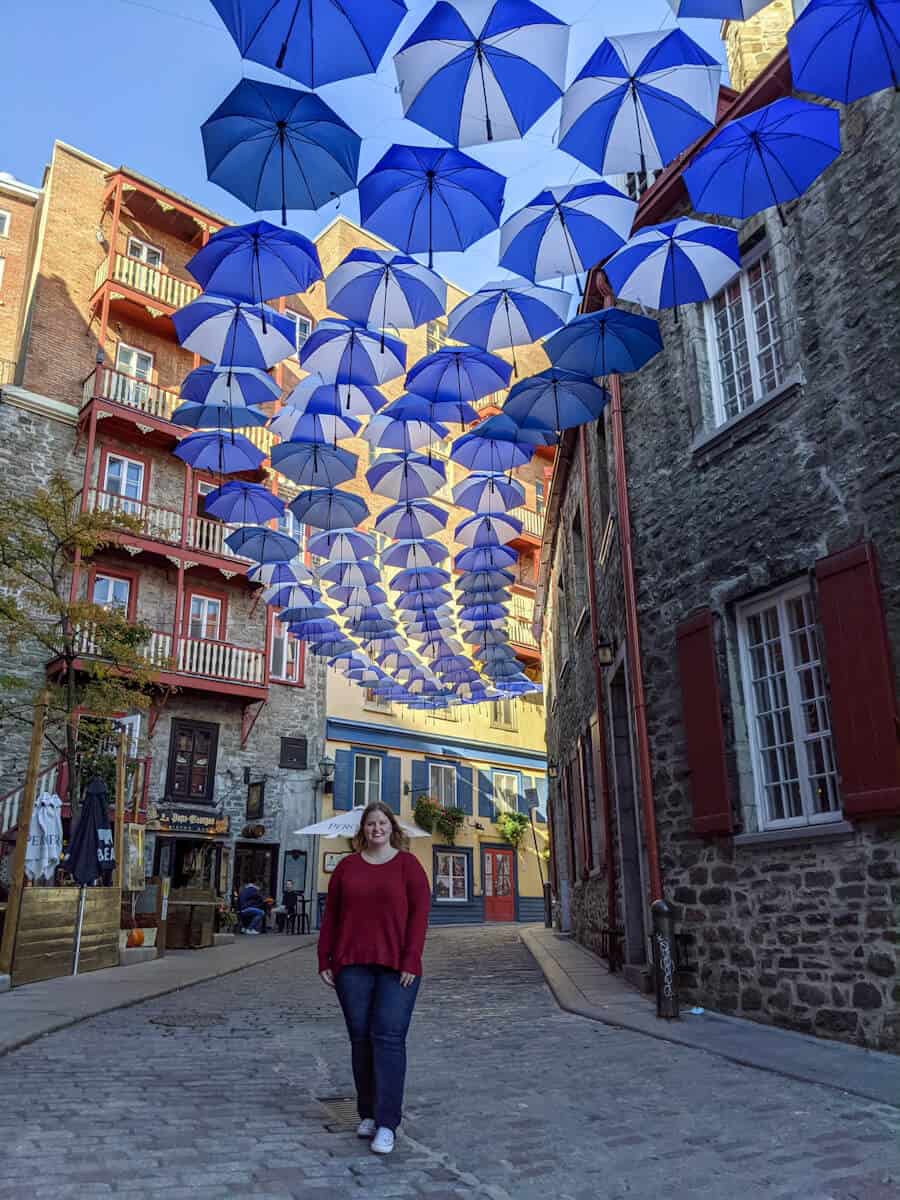when planning my 3 day quebec city itinerary, I had to stand under these blue and white umbrellas on the famous umbrella street in old quebec